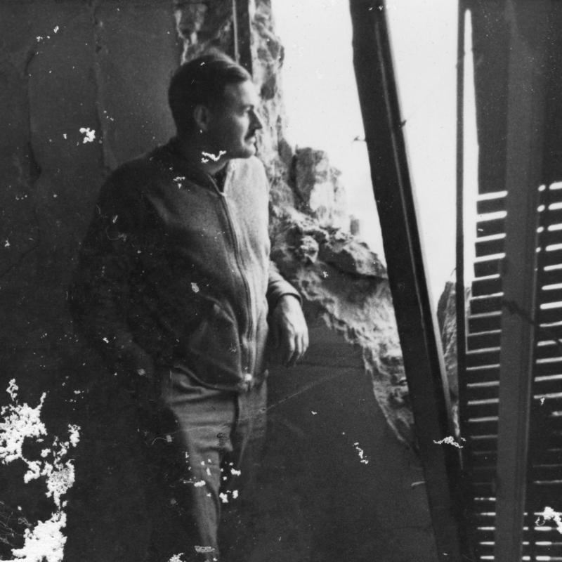Hemingway looks out through a bomb-damaged wall during the Spanish Civil War, c 1937-38